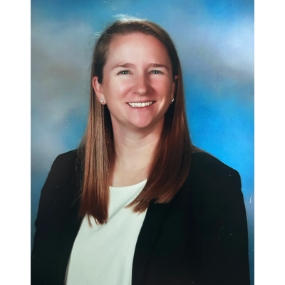 Smiling woman with long hair in professional attire against a blue backdrop.