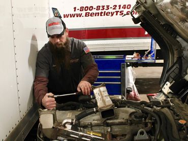 Mechanic working on an engine inside a garage.