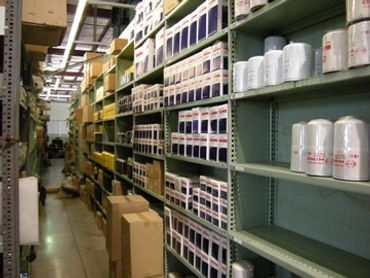 Warehouse aisle with shelves storing boxes and cans.