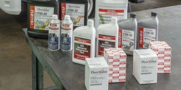Various Isuzu branded automotive fluids and products arranged on a table.