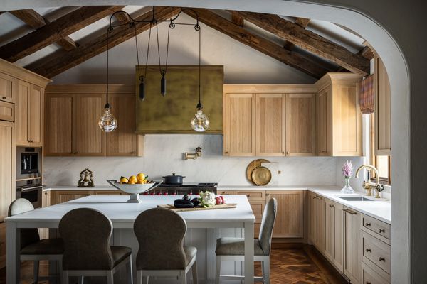 Luxury custom kitchen with natural wood cabinetry, exposed beam ceiling, and a large white island.