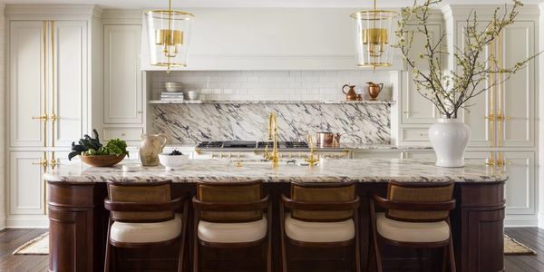 Elegant custom kitchen with white, inset cabinets and a dark island highlighted with brass hardware.