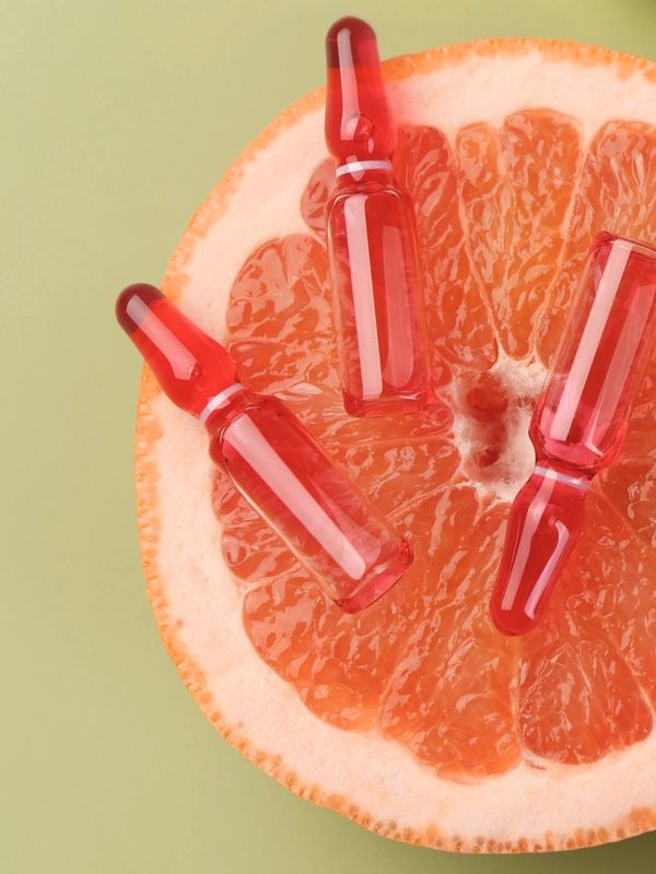 Three red wellness infusion on a halved grapefruit against a light green background.