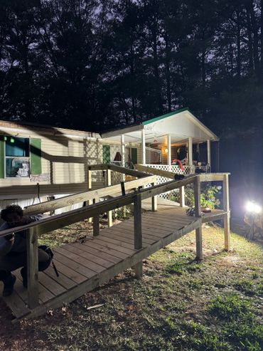 Newly built wooden wheelchair ramp leading to a mobile home at night.