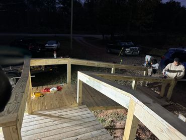Two men working on building a wooden ramp outdoors at night.