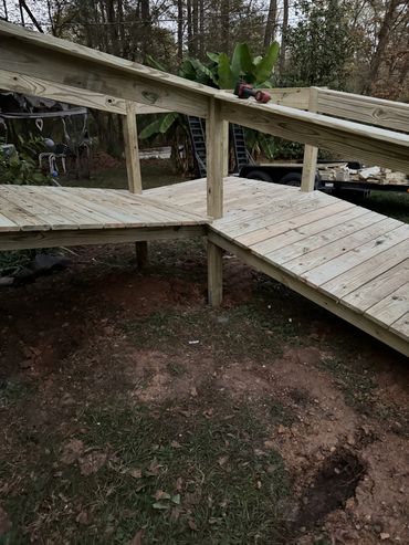 Wooden ramp with handrails under construction in a backyard.