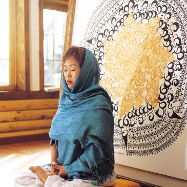 Artist Heesung Lee in meditation in front of her painting 