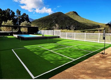 Wide view of outdoor leisure area of badminton court, putting green, swimming pool, and braai area