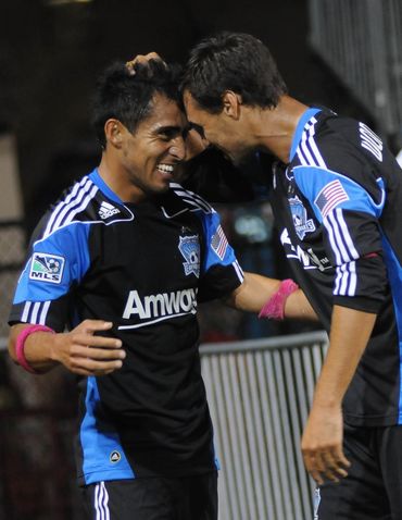 Two San Jose Earthquakes players celebrate together after a goal