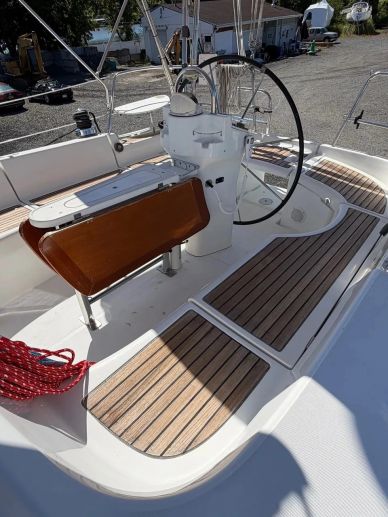 Clean sailboat cockpit with wooden flooring and steering wheel.