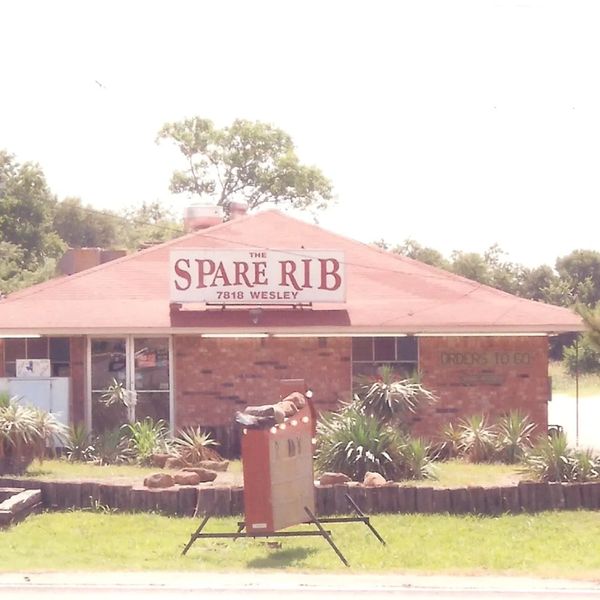 Brick barbecue restaurant named The Spare Rib with a smoking chimney and outdoor sign.