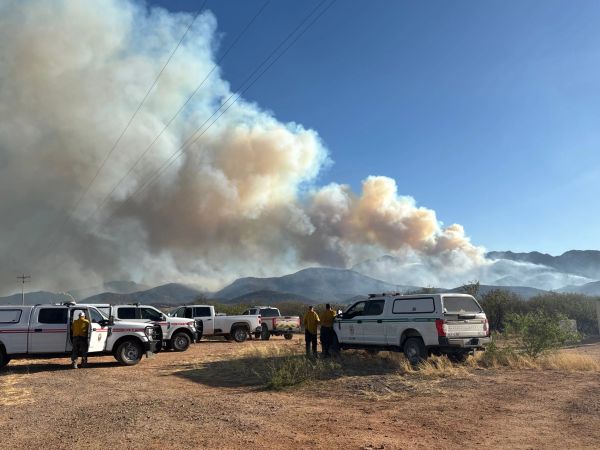 Firefighters prepare to battle a wildfire near mountains.