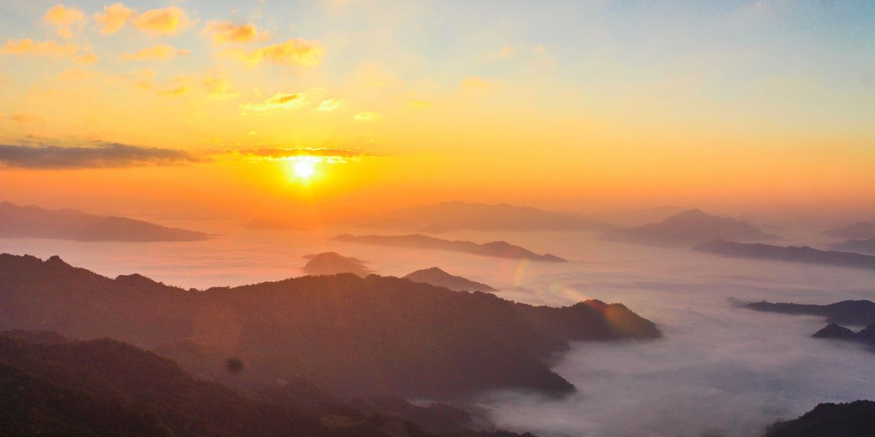 Sunrise over misty mountains with a colorful sky.