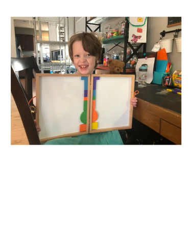 Young boy holding up a paper and proudly smiling.