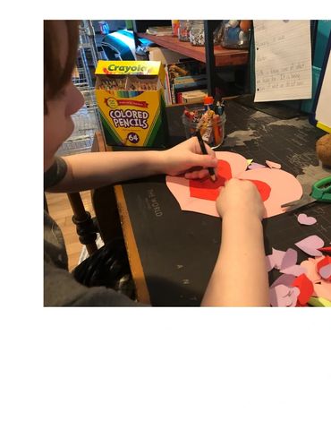 Young boy sitting at a desk making a Valentines.