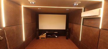 Modern home theater room with ambient LED strip lighting and a projector screen.