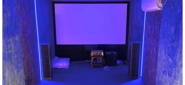 Modern home theater room with blue LED lighting and projector screen.