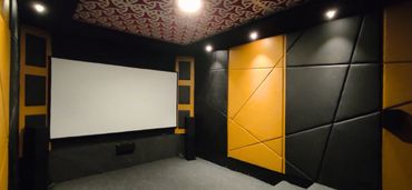 Modern home theater room with acoustic panels and large screen.