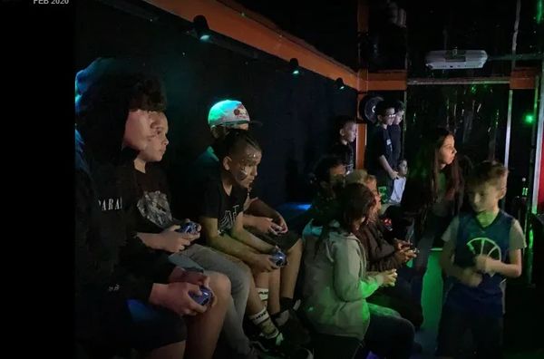 Kids playing video games in a dimly lit party setting.