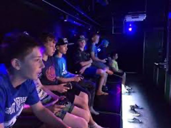 A group of young people playing video games in a dark room.