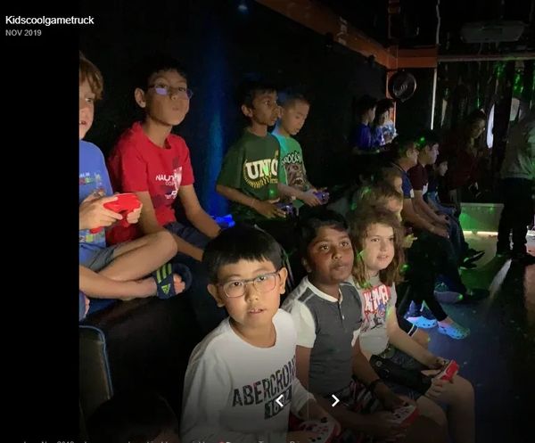 Children engaged in a gaming session inside a dark room, holding controllers.