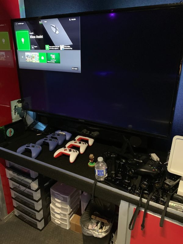Gaming setup with multiple controllers and a TV displaying Xbox Assist.
