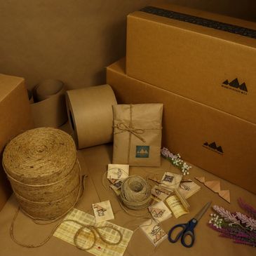 Eco-friendly packaging materials including cardboard boxes, kraft paper, and twine.