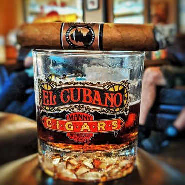 El Cubano glass with a cigar on top of it
