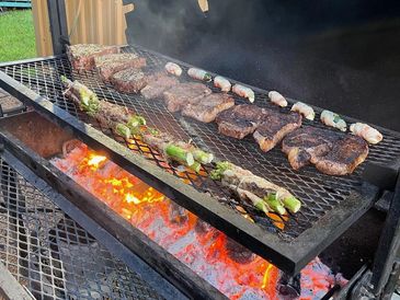 bbq pit with steaks and veggies on it