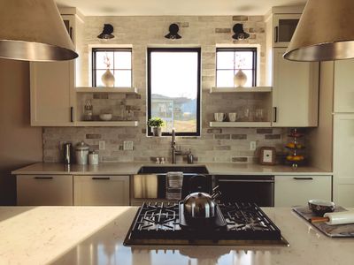 Modern kitchen with brick backsplash and stainless steel stove and sink.