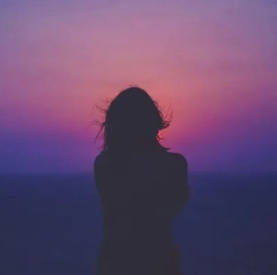 Silhouette of a person against a vibrant purple and pink sunset sky.