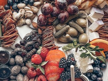 A colorful charcuterie board with fruits, nuts, and cheeses.