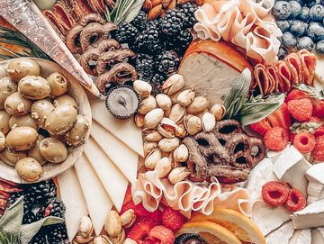 A colorful charcuterie board with fruits, nuts, cheeses, and meats.