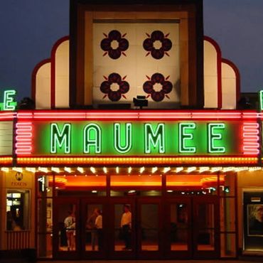 Historic Maumee Theater lit up at night with neon signs.
