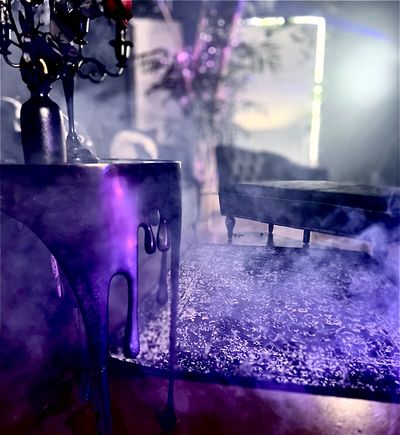 A dimly lit room with purple smoke and gothic furniture.