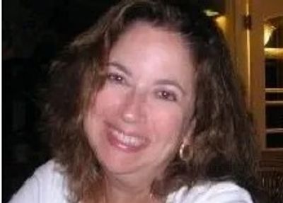 Smiling woman with curly hair in a relaxed indoor setting.