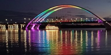 Quad Cities I-74 bridge, its lights reflecting rainbow onto the river. Credit to Michelle O'Neill.