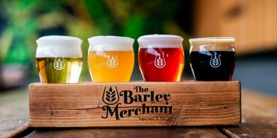 Four craft beer samples in a wooden tray from The Barley Merchant.