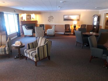 Common area living room with a fireplace, tables and comfortable chairs