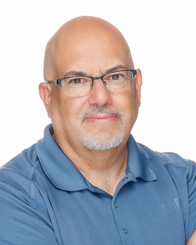 Smiling man with glasses in a blue polo shirt against a white background.