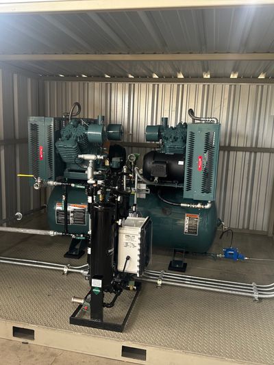 Industrial air compressor setup inside a metal shed.