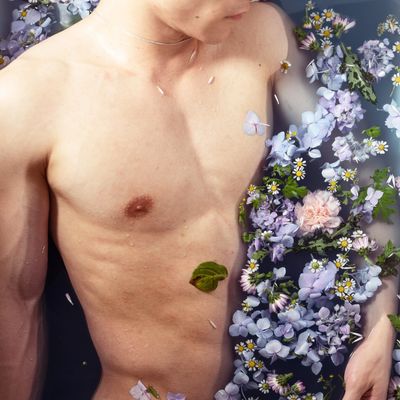 Bare-chested person surrounded by purple flowers.