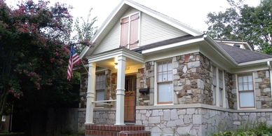 Stone house with a front porch and American flag.