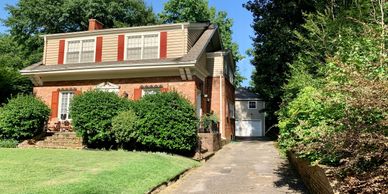 Two-story brick house with green bushes and a driveway.