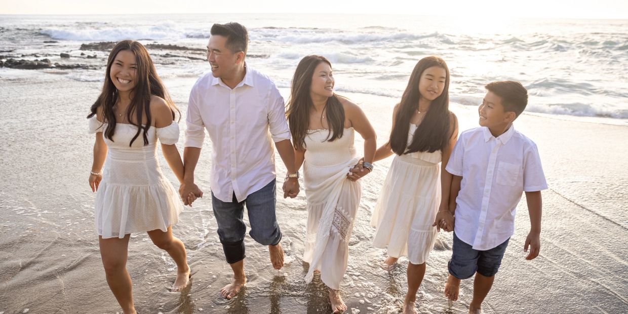 Family holding hands and smiling at the beach.