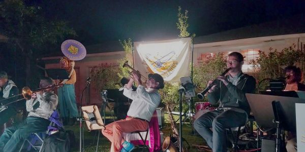 A Dixieland band plays jazz music at night on a lawn