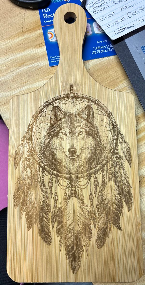 Wooden cutting board with engraved wolf and dreamcatcher design.