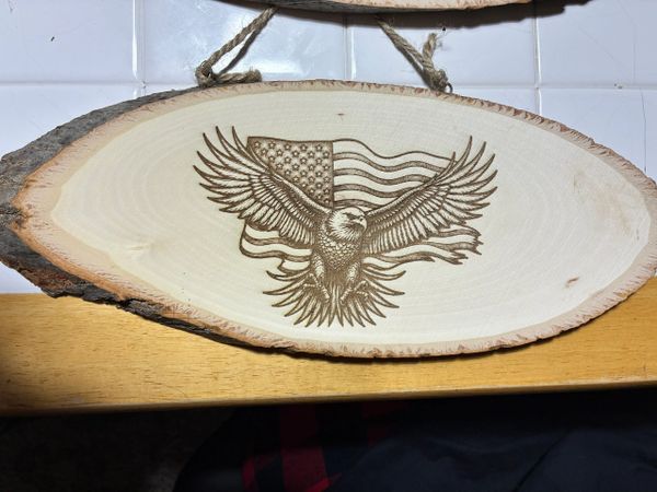 Wood plaque with an eagle and American flag engraving.
