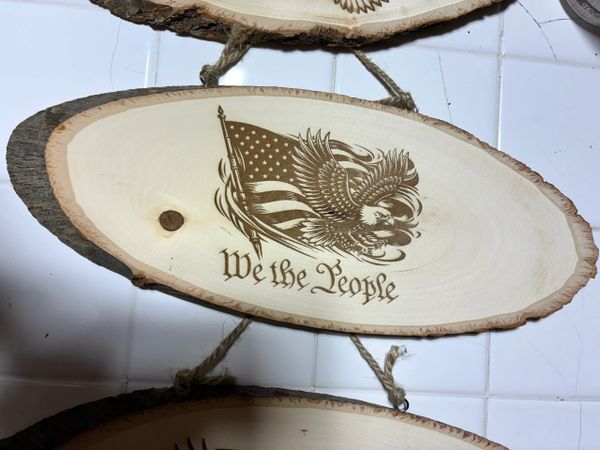 Wooden plaque with an eagle, American flag, and 'We the People' text.