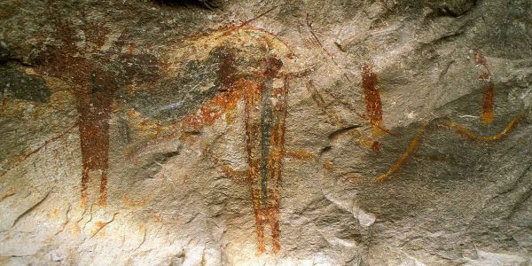 Ancient red ochre cave paintings on rock surface.